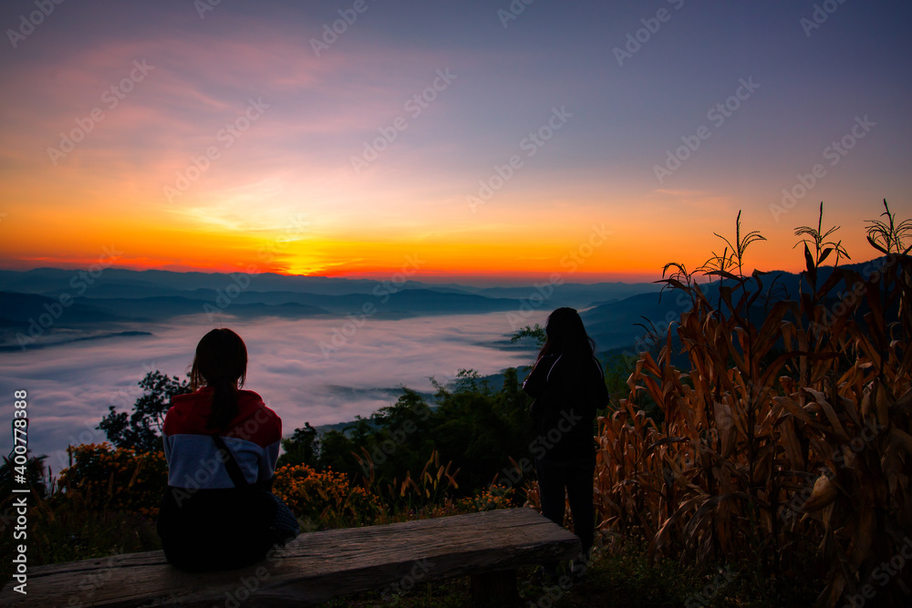 The silhouette of a woman sitting in front of the sunrise on the hill with the sea of ​​clouds In the north of Thailand, Doi Samer Dao, Nan Province
