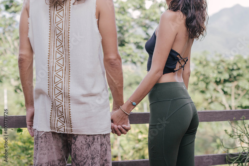 White hippie couple holding hands in yoga clothers during sunset time in the nature