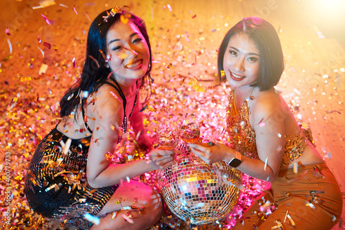 Attractive young Asian women smiling at camera when posing with disco ball and wine glasses
