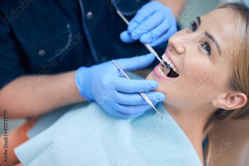 Jolly young woman being examined by dentist