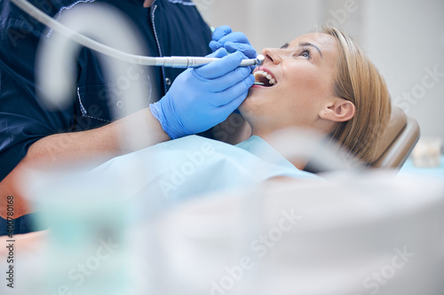 Dentist treating young attractive woman with machine
