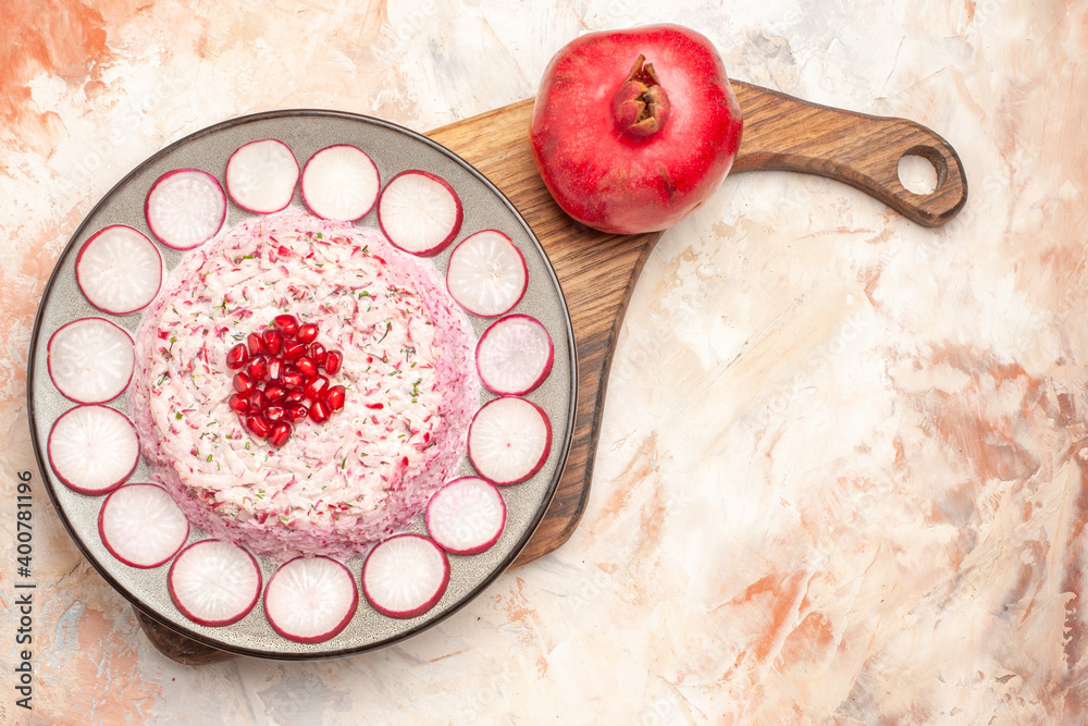 Overhead view of delicious chicken salad served with chopped red radishes and pomegranate on white background