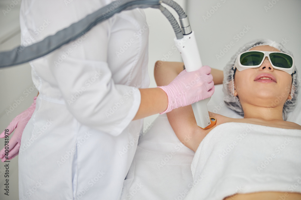 Naklejka premium Doctor directing the laser beam on the patient underarm area