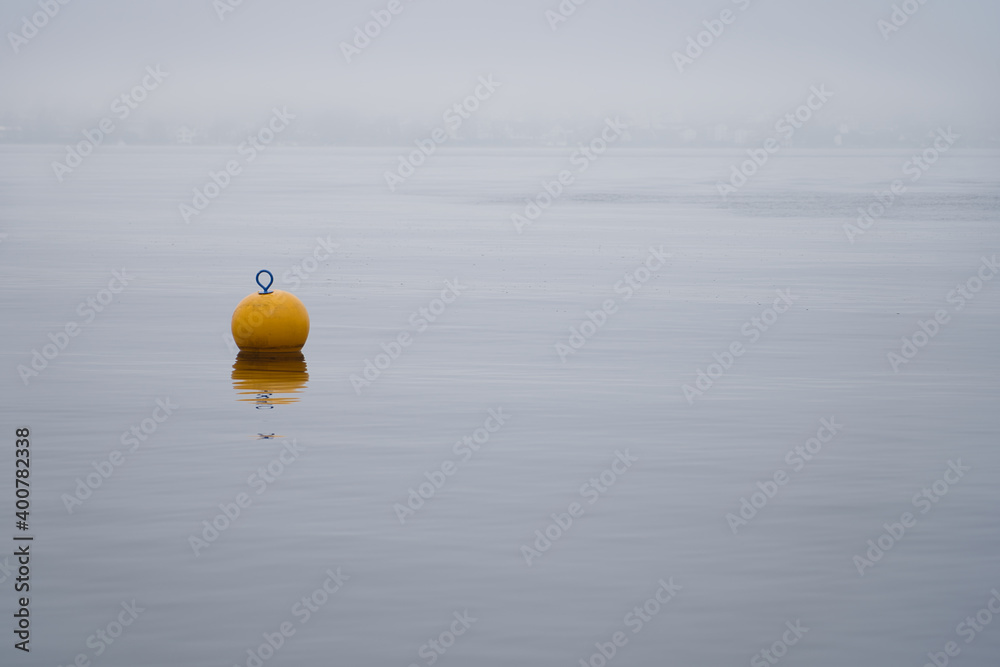 Gelbe Boje im Nebel am See