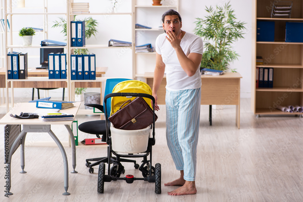 Young male employee looking after newborn at workplace Young male employee looking after newborn at workplace