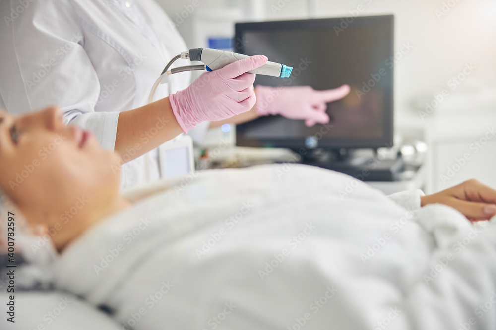Cosmetician in sterile gloves tipping the touch screen