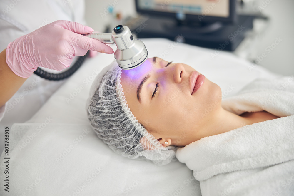 Doctor using a photo beauty device in cosmetology Doctor using a photo beauty device in cosmetology