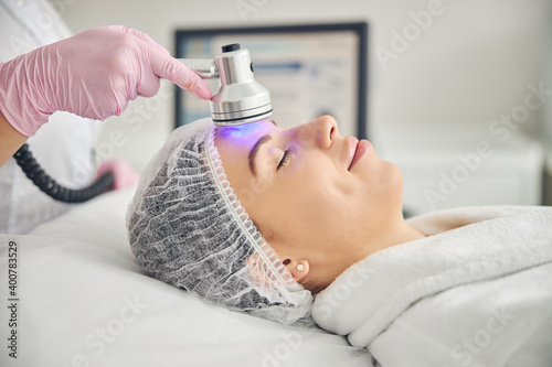 Doctor applying a photo beauty device on her patient