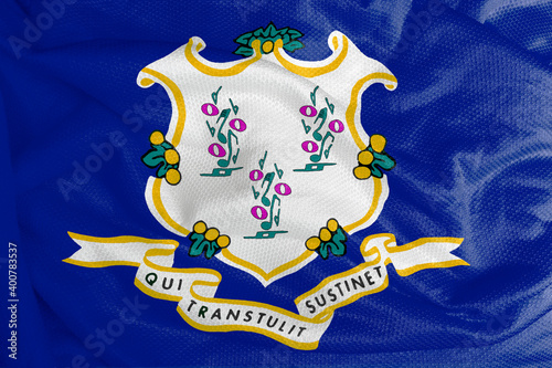 The Connecticut flag has a white shield topped by three vines on a blue field. The ribbon below the shield depicts Connecticut’s motto. The colors of the flag are blue, white and yellow.