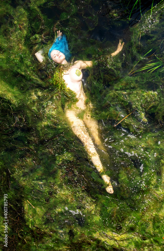 Young woman with blue hair drifting elegantly in the algae swamp photo