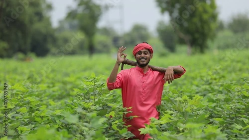 Young indian farmer holding farm equipment in hand at cotton field photo