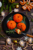 An appetizer for the New Year's table made in the form of tangerines on a dark plate against a background of decorations and garlands. Vertical.