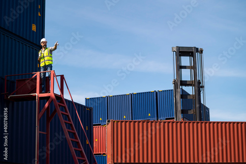 Obraz na płótnie Logistics engineer stand on and Pointing up around Shipping container stacker in commercial transport port w salonie
