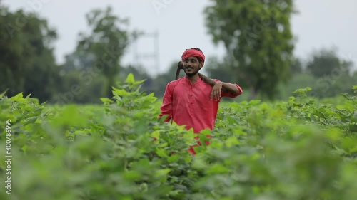 Young indian farmer holding farm equipment in hand at cotton field photo