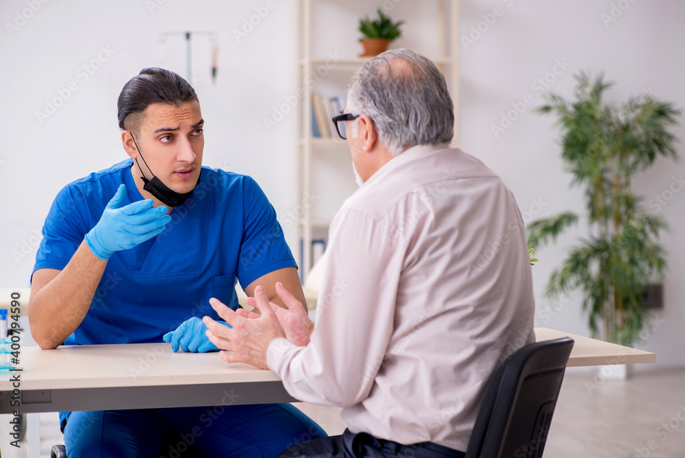 Fototapeta premium Old patient visiting young male doctor