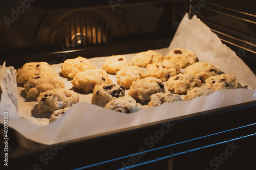 Homemade oatmeal ruddy cookies with raisin on the baking sheet in the oven close-up photo