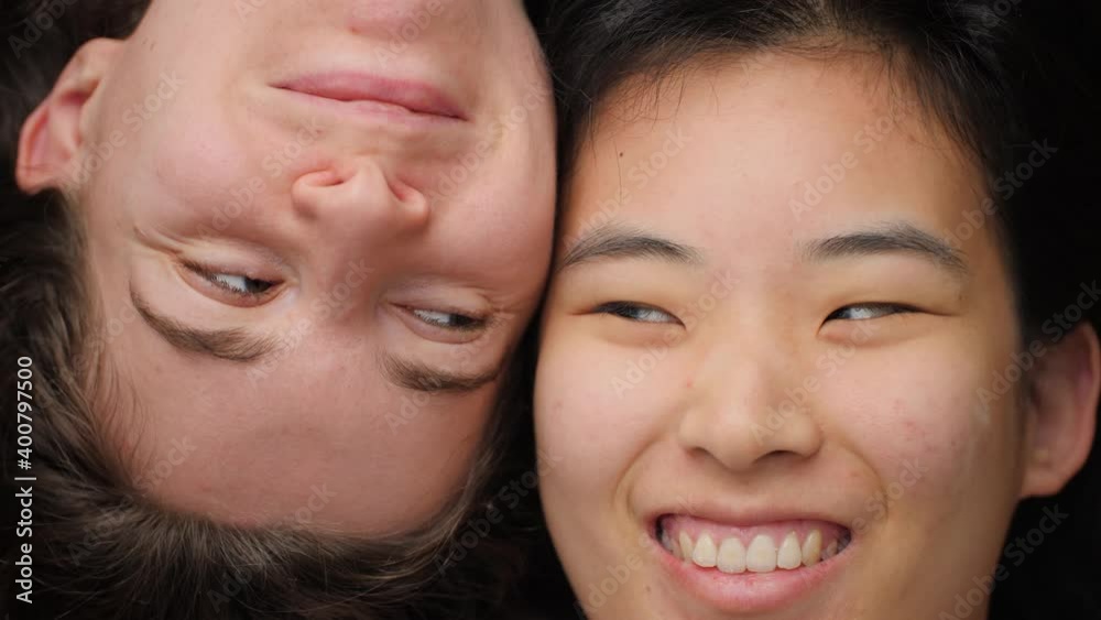 Happy and young Asian and Caucasian women looking at each other and smiling. Portrait of two girls having fun and laughing. Concept of interracial friendship, female mixed race homosexual couple. 4K. Happy and young Asian and Caucasian women looking at each other and smiling. Portrait of two girls having fun and laughing. Concept of interracial friendship, female mixed race homosexual couple. 4K.