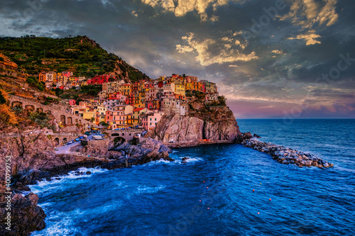 Colorful traditional houses on the rock over Mediterranean sea on dramatic sunset, Manarola, Cinque Terre, Italy