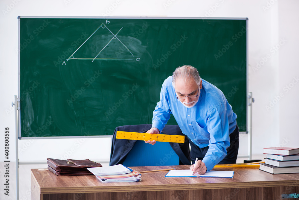 Old male geometry teacher holding triangle Old male geometry teacher holding triangle