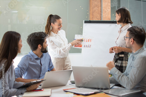 Young businesswoman presenting some results on a paper document to group of people in a meeting room
