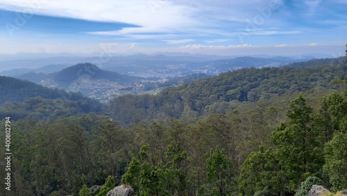 beautiful scenic view from dottabetta peak of green forest hill mountain with blue sky rain mist clouds background