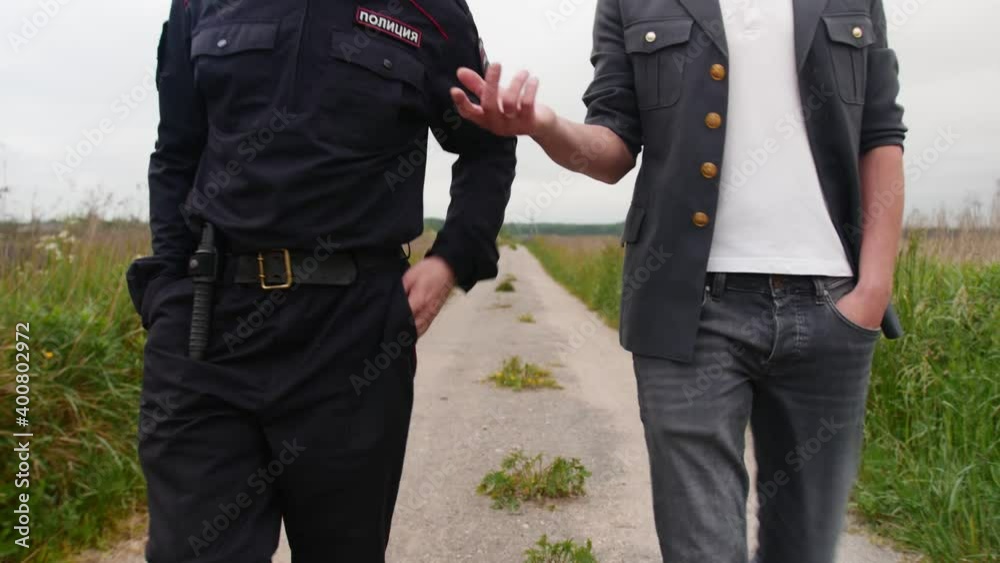 Two Russian police officers are walking along the path in the countryside. Two Russian police officers are walking along the path in the countryside.