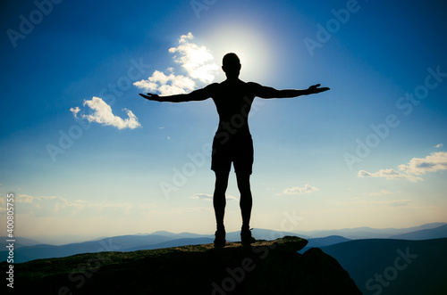 man stands on top of a mountain with open hand