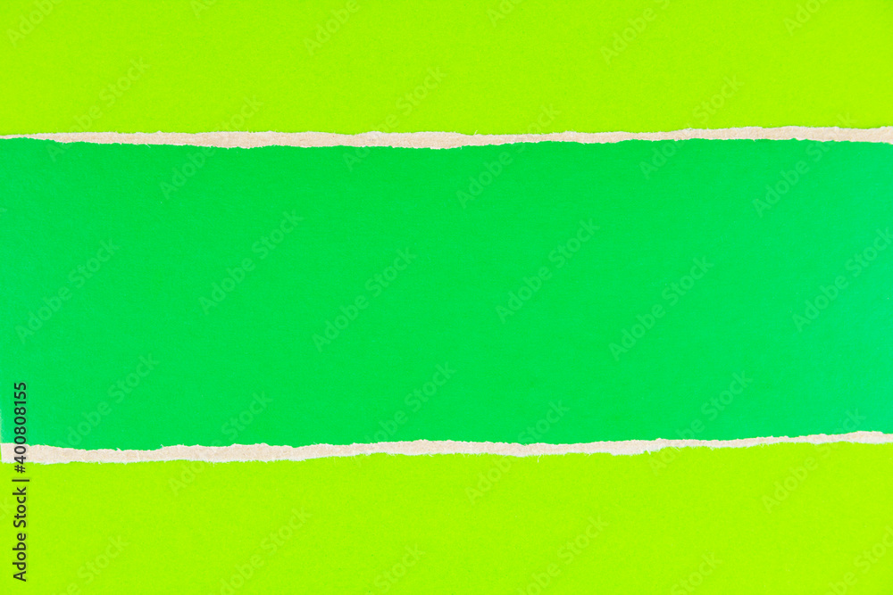 Torn piece of green cardboard on green paper background. Stripe of green cardboard with copy space for text. Torn piece of green cardboard on green paper background. Stripe of green cardboard with copy space for text.