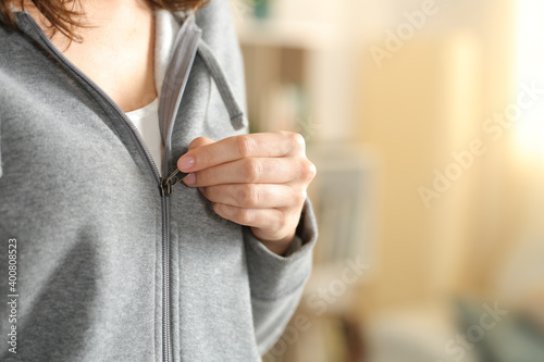 Woman hand dressing closing zipper of hoodie at home