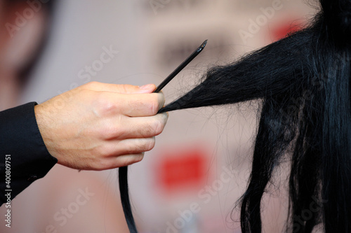 Hairdresser hands doing woman black hair using comb