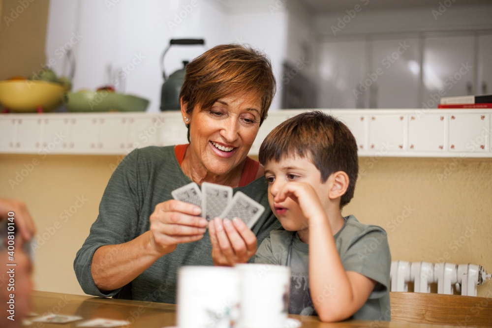 Grandson and grandmother talking with complicity while she plays cards. Grandson and grandmother talking with complicity while she plays cards.