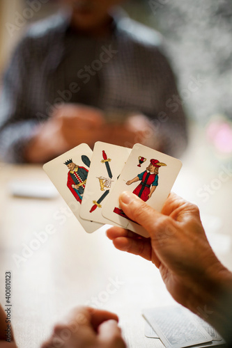 Hand with Italian three cards. Family playing board game indoors.