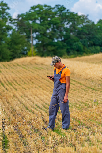 Man-farmer stands in field with golden wheat. Agriculture concept.