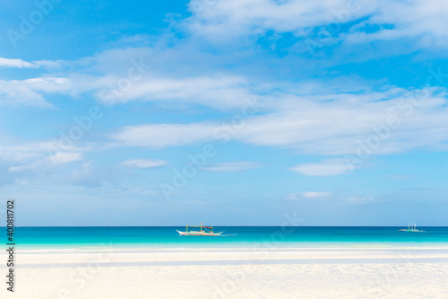 Tropical beach and beautiful sea with boats. Blue sky with clouds in the background.