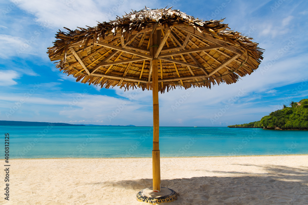 Straw sun umbrella on the tropical sand beach on Boracay island, Philippines. Summer vacation concept.