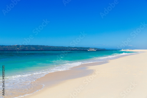 Tropical beach and beautiful sea with boats. Blue sky with clouds in the background.