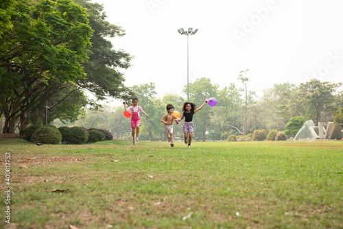 Foto Group of kids running in the spring field at public park with balloon