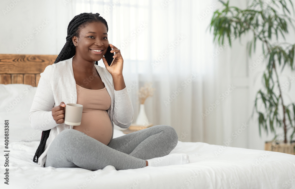 Pregnant Pastime. Smiling Black Expectant Mother Talking On Cellphone And Drinking Tea Pregnant Pastime. Smiling Black Expectant Mother Talking On Cellphone And Drinking Tea