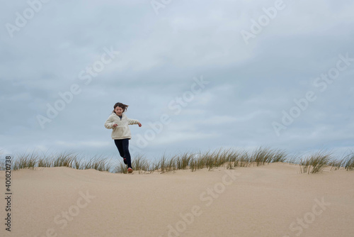 cute young girl running in the dunes in autumn