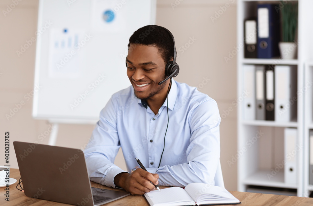 Cheerful black guy crisis manager working in front of laptop Cheerful black guy crisis manager working in front of laptop