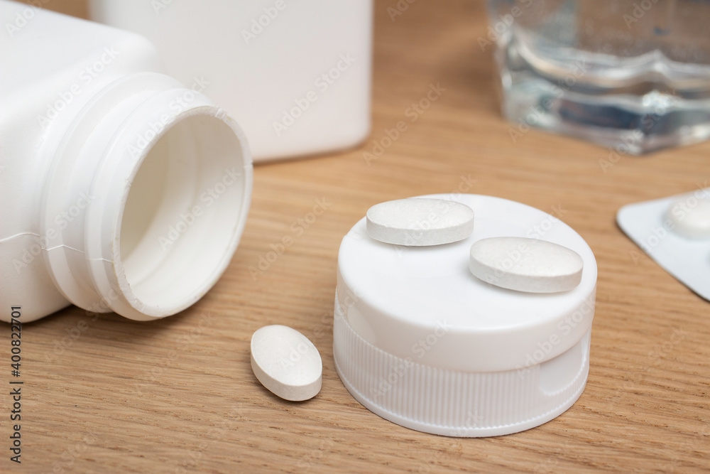 White pills of antibiotic, painkiller, vitamin supplements, zinc on wooden table, close-up view White pills of antibiotic, painkiller, vitamin supplements, zinc on wooden table, close-up view