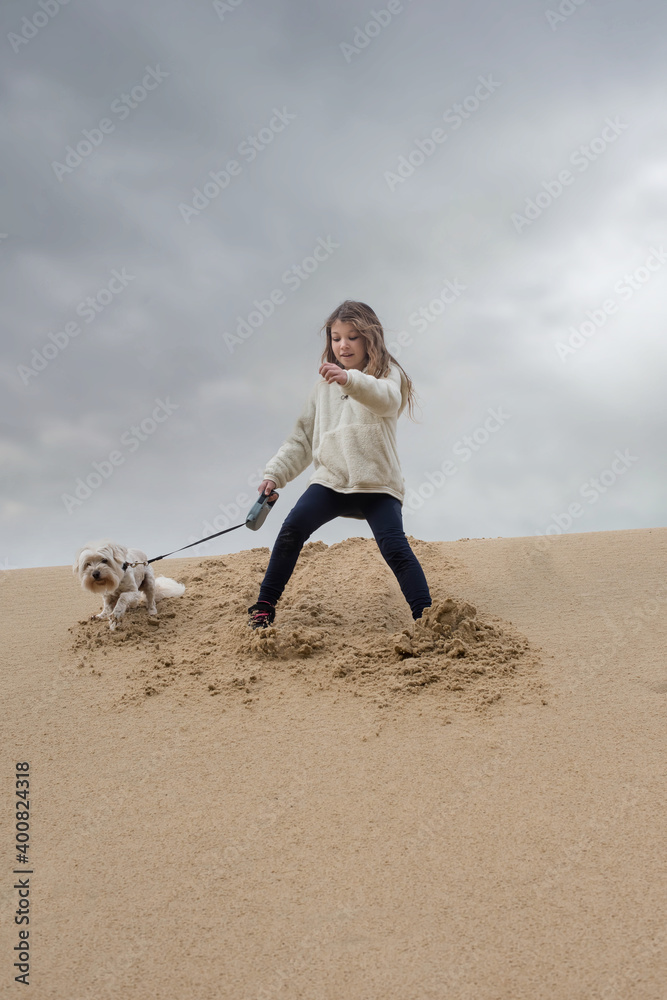 cute young girl running in the dunes with her dog in autumn cute young girl running in the dunes with her dog in autumn
