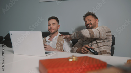 Happy gay couple or best friends playing video games. Gift in the foreground. High quality photo photo