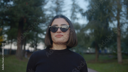 Short hair beautiful young woman walks down the street with sunglasses