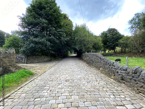 Looking up  Lee Lane with stone cobbles  and dry stone walls  on a cloudy day in  Shibden Valley  Halifax  UK