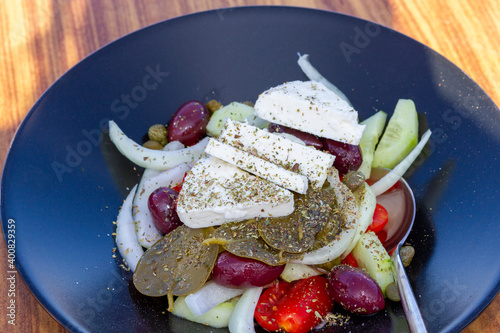 Greek salad (choriatiki) and grape leaves, on a table served with greek and mediterranean cuisine, in Oia village, Santorini island, Greece, Europe.