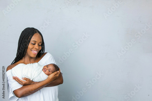 A beautiful African-American new mom holding and cradling her newborn son and looking at him with love and affection