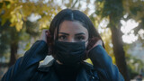 Young woman on the street during pandemic period and she is taking off her black mask and while looking at camera. Covid-19 concept