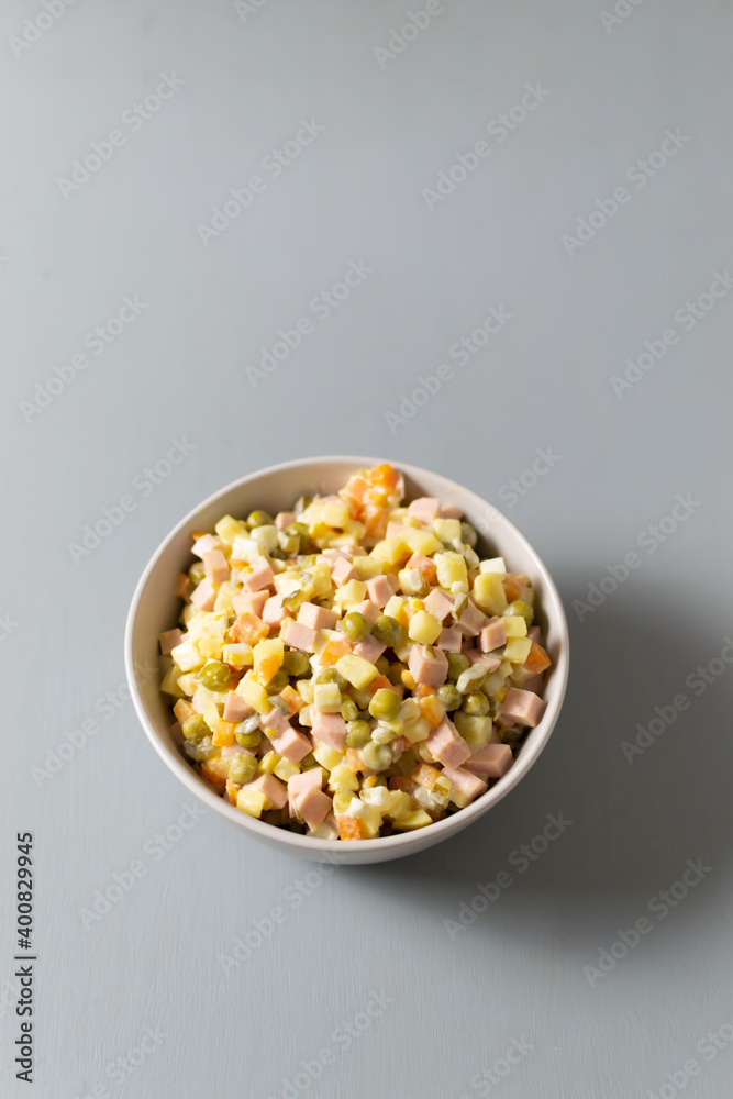 Olivier salad russian in a bowl on a gray background. Traditional Russian cuisine. Copy space. Vertical orientation. Olivier salad russian in a bowl on a gray background. Traditional Russian cuisine. Copy space. Vertical orientation.