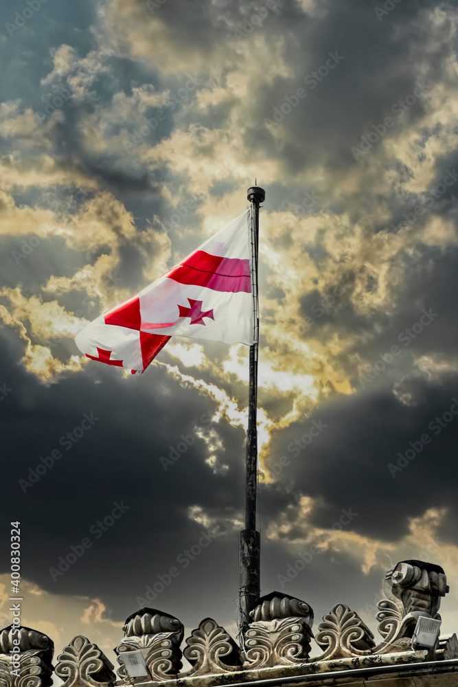 Republic of Georgia flag flying against dramatic stormy sky atop ornate building